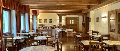 A restaurant with wooden interiors, multiple dining tables, and chairs.