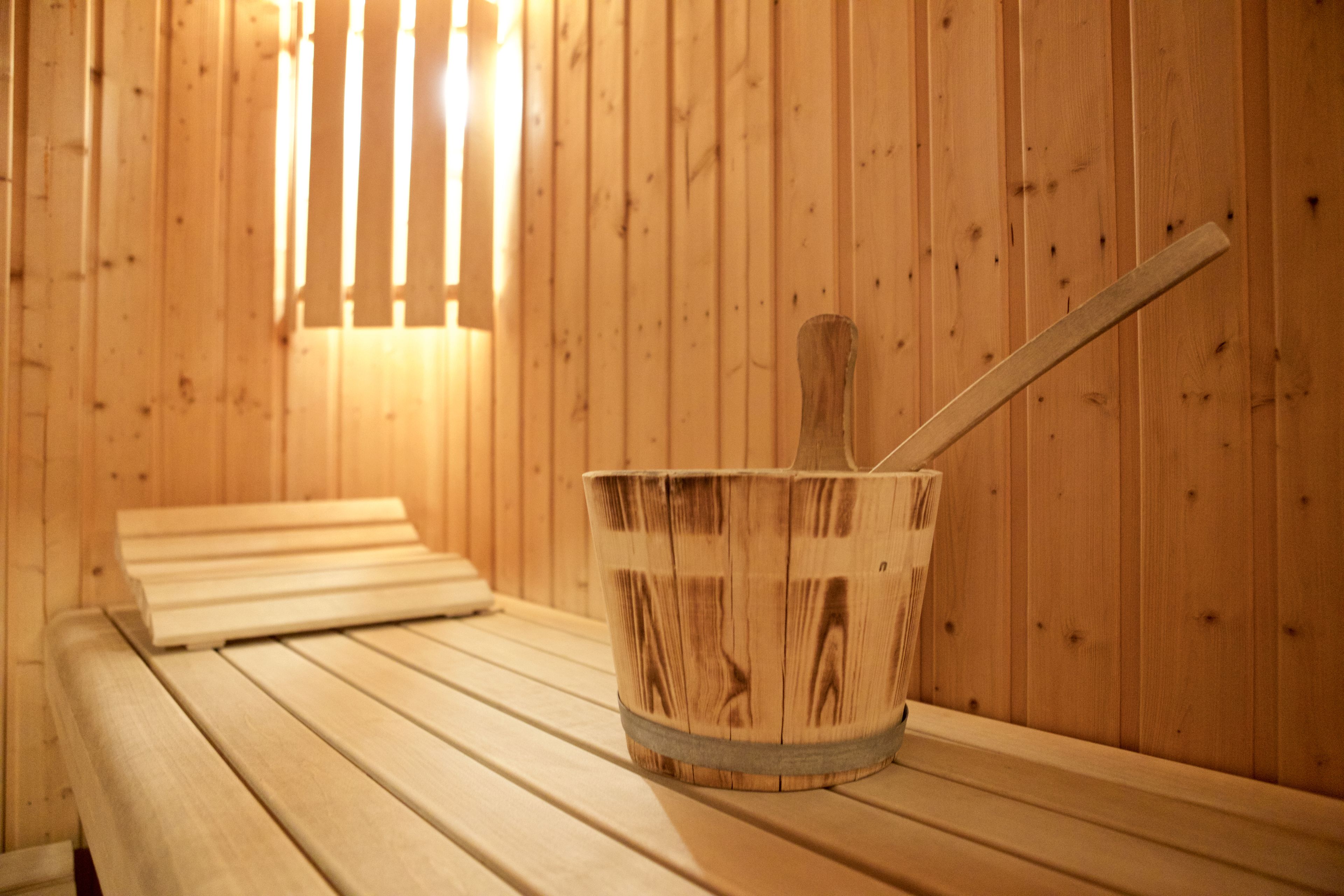 Una sauna de madera con bancos y un cubo de madera con una cuchara.