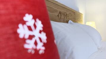 Una cama con ropa blanca y una almohada roja con un diseño de copo de nieve blanco.
