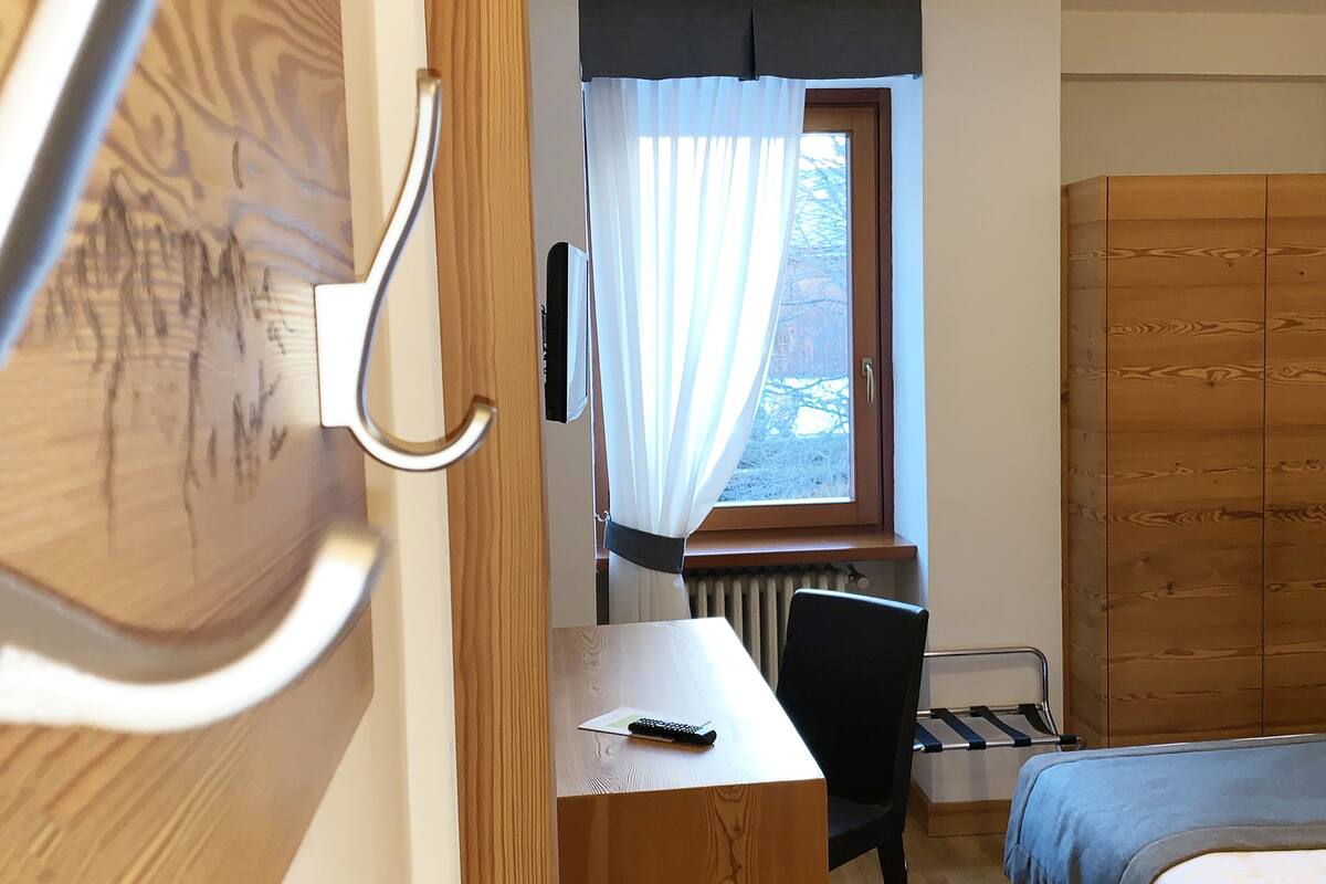 A room with a wooden desk, a bed, and a window with curtains.