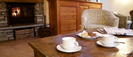 Una mesa de madera con dos tazas y platillos blancos, un plato de galletas y un periódico.