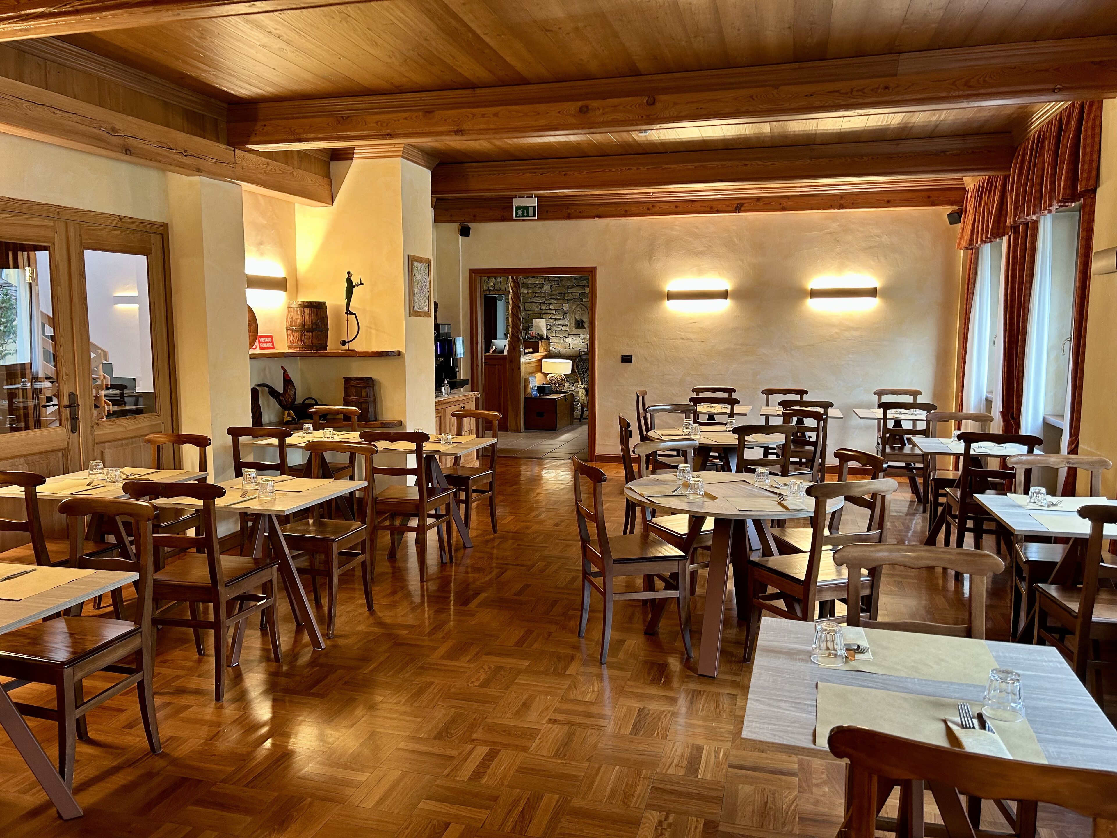 Un restaurante con muebles de madera, suelo de espiga y pared de piedra.