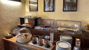 Un bufé con diversas opciones de comida, incluyendo carnes, quesos y pan, con etiquetas claras y una selección de salsas.