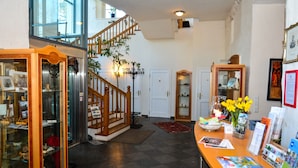 A spacious lobby with a staircase, a reception desk, and a display case with various items.