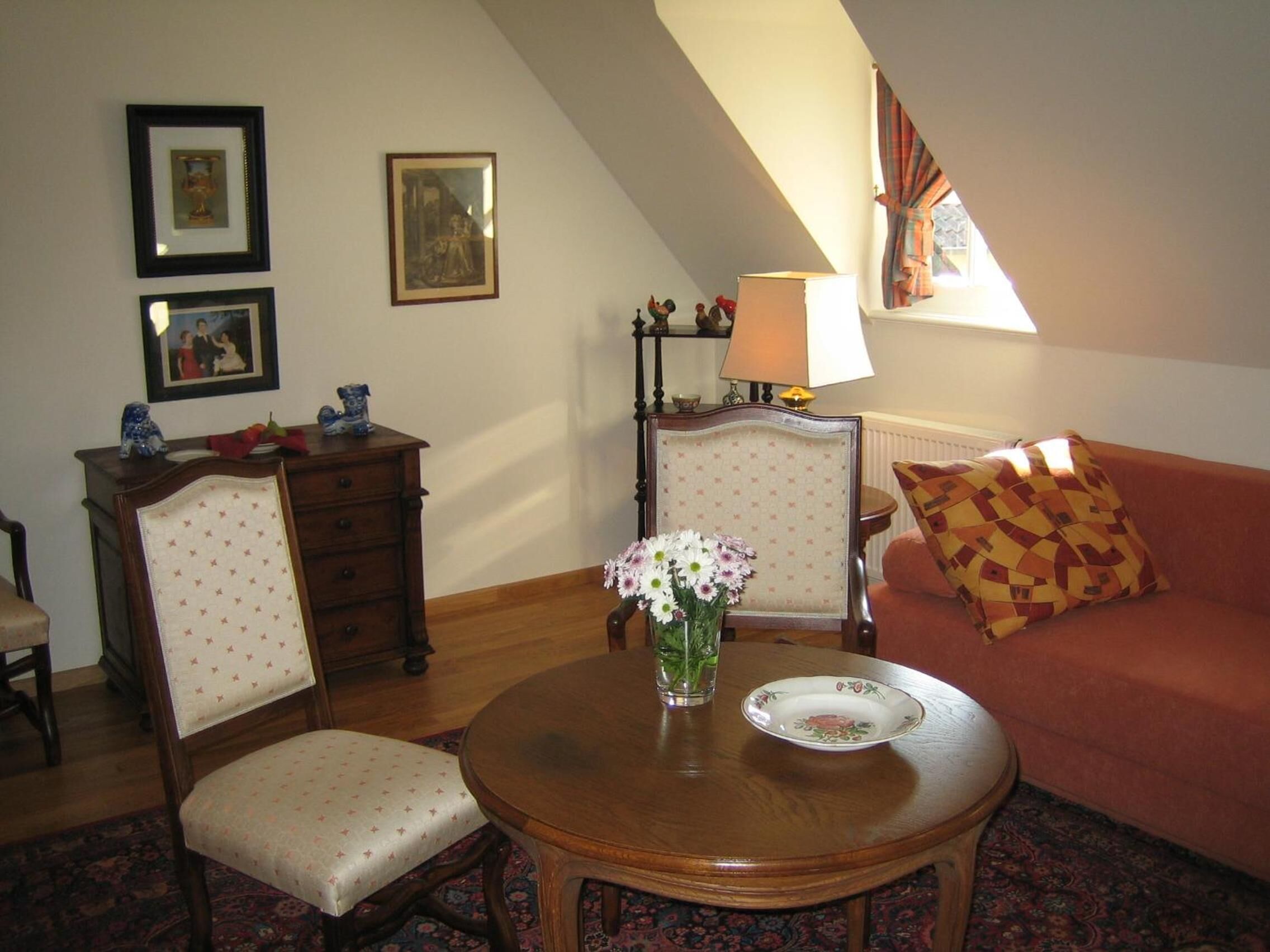 Una sala de estar acogedora con una mesa redonda de madera, dos sillones, un sofá y una ventana con cortinas.