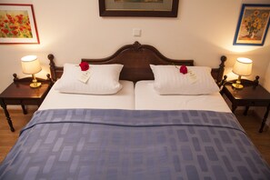 Ein Doppelbett mit Holzfußteil, zwei Nachttische mit Lampen und eine blau gemusterte Bettdecke.