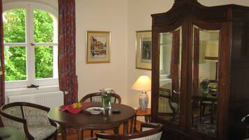 A dining room with a round table, chairs, a vase with flowers, a lamp, and a mirror.