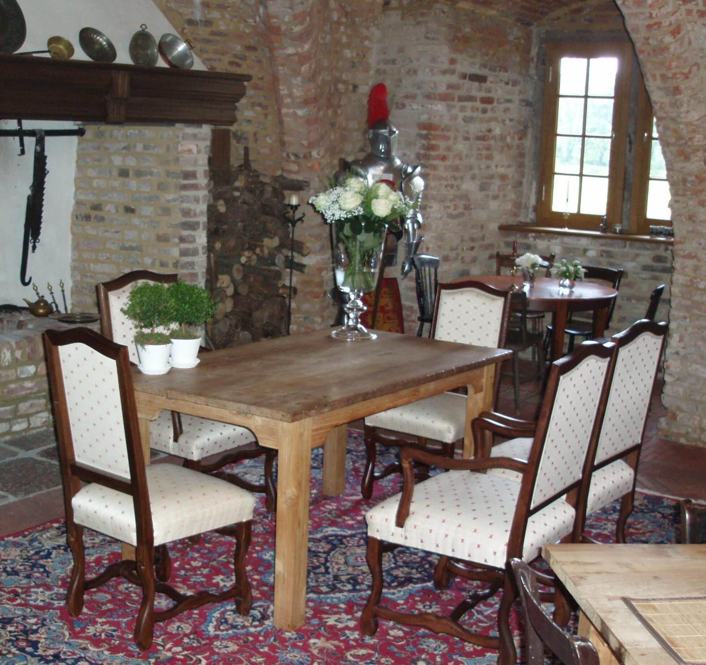 Une salle à manger traditionnelle avec une table en bois et six chaises, un arrangement floral au centre de la table et un mur en briques.