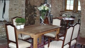 Une salle à manger traditionnelle avec une table en bois et six chaises, un arrangement floral au centre de la table et un mur en briques.