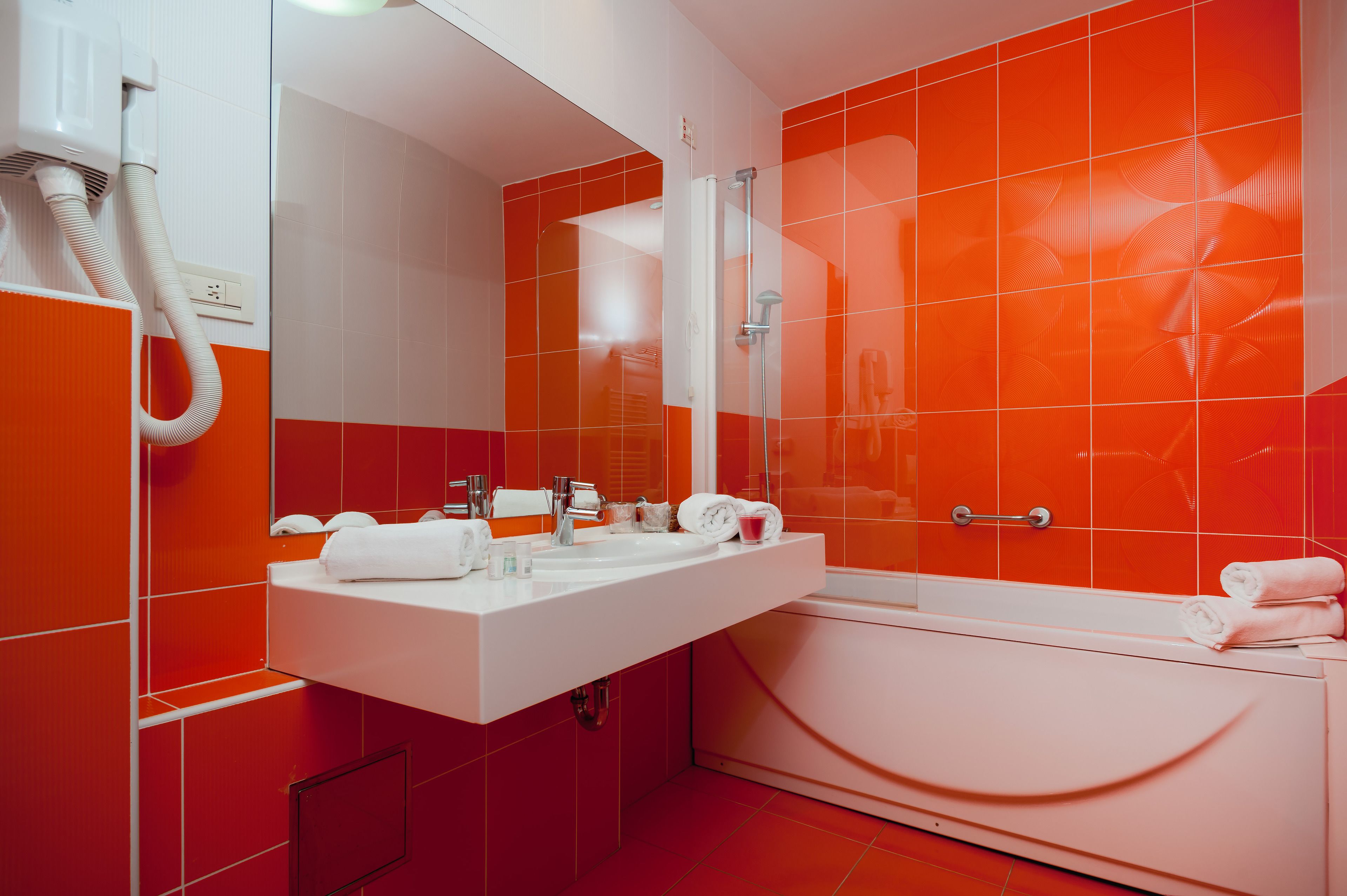 A modern bathroom with a white sink, two mirrors, and a bathtub.
