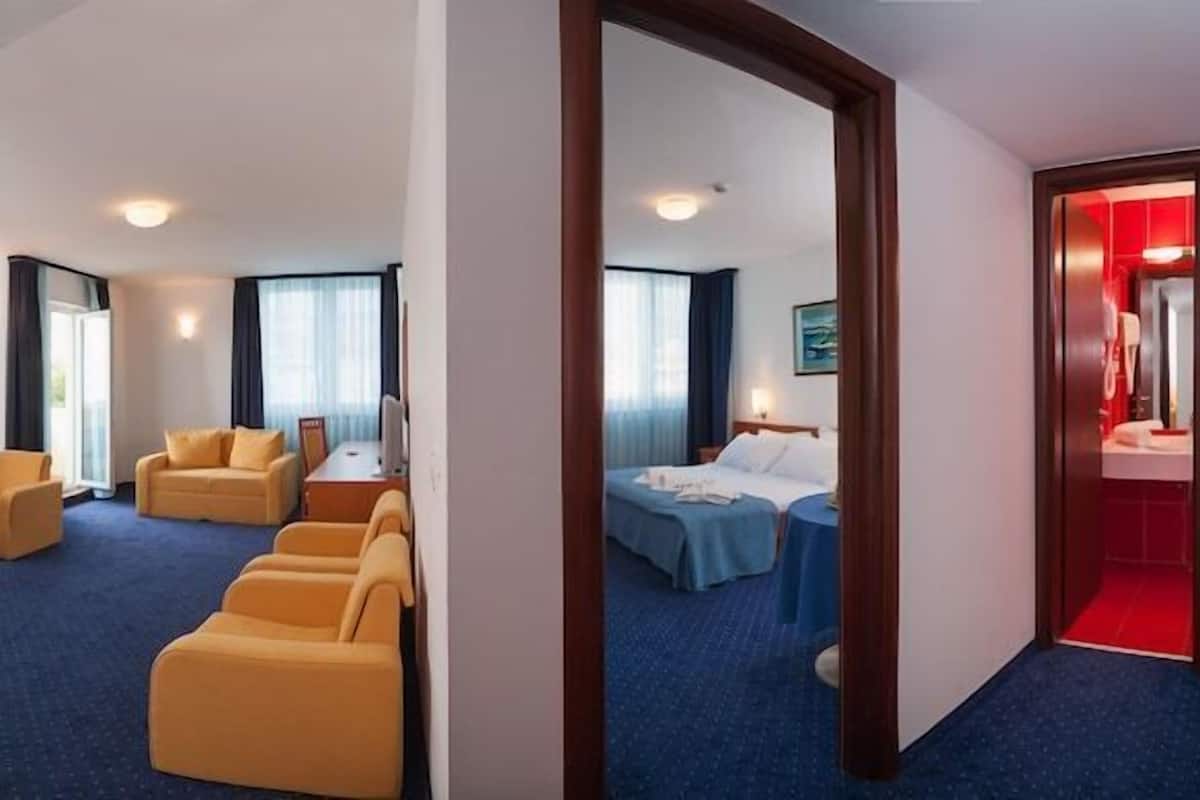 A hotel room with a bed, a desk, a chair, and a sofa.