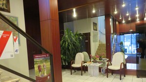 Eine Lobby mit einer Rezeption, einer Sitzecke und einer Treppe.