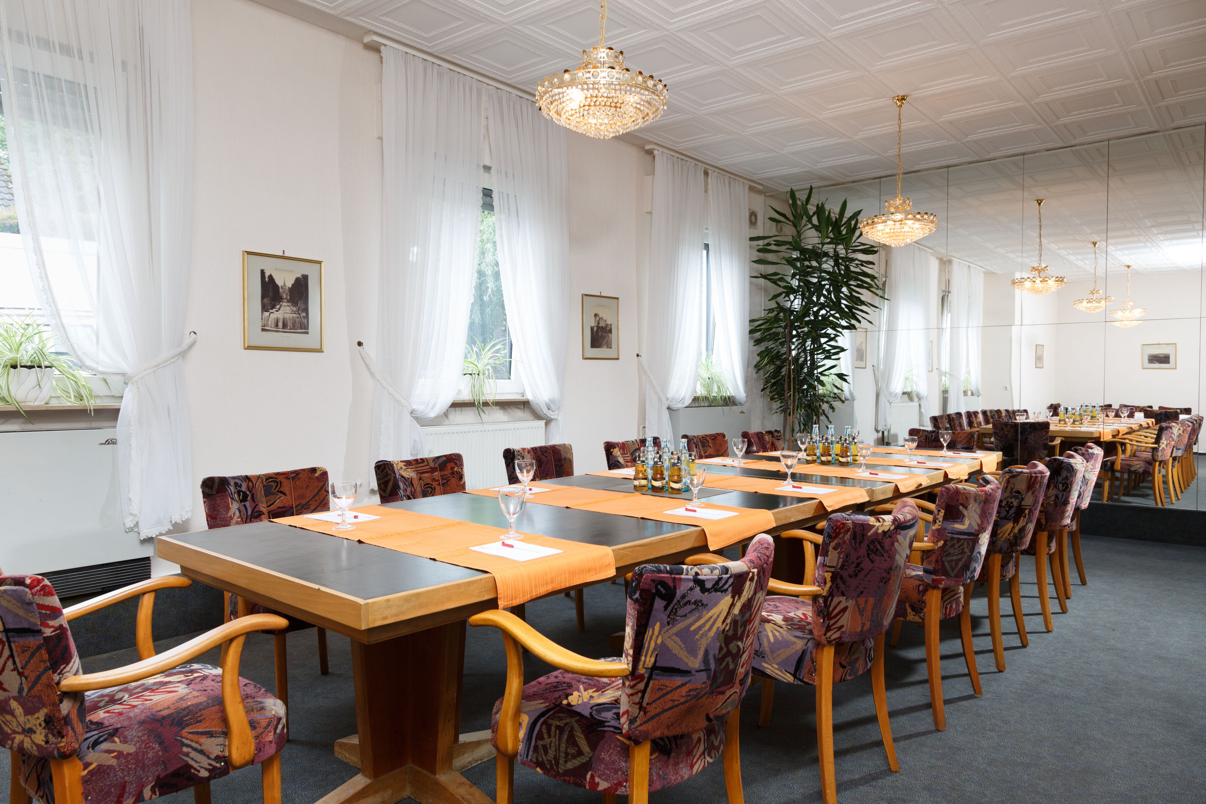 A conference room with a long table, multiple chairs, and hanging chandeliers.