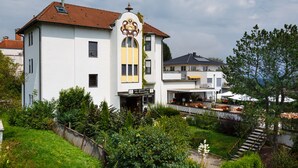 Ein weißes Gebäude mit rotem Dach, einem Schild für ein Restaurant-Café und einer Treppe zu einem überdachten Bereich mit Außenplätzen.