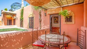 Un patio exterior acogedor con una mesa redonda y sillas, una cesta colgante y una puerta decorativa.