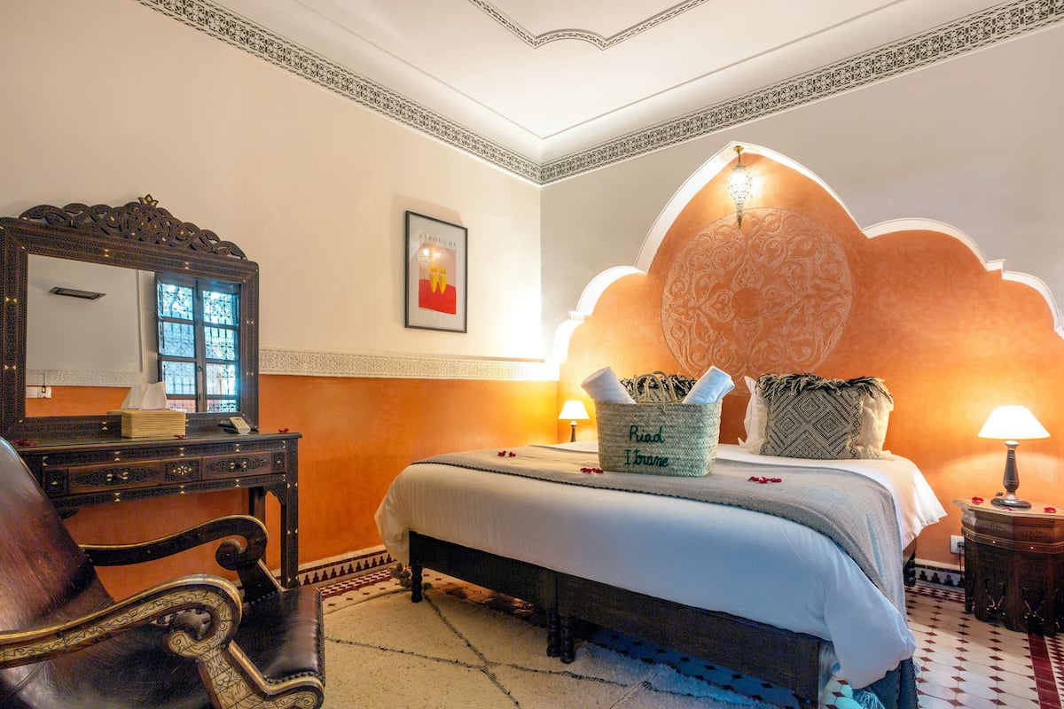 Una habitación de hotel con cama, escritorio, silla y un espejo grande.