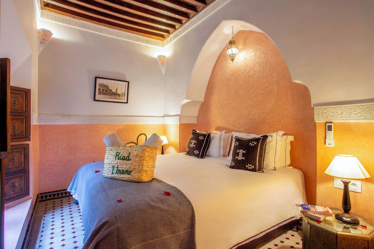 Una habitación de hotel con una cama grande, una lámpara de noche, un teléfono en la pared y un adorno decorativo.