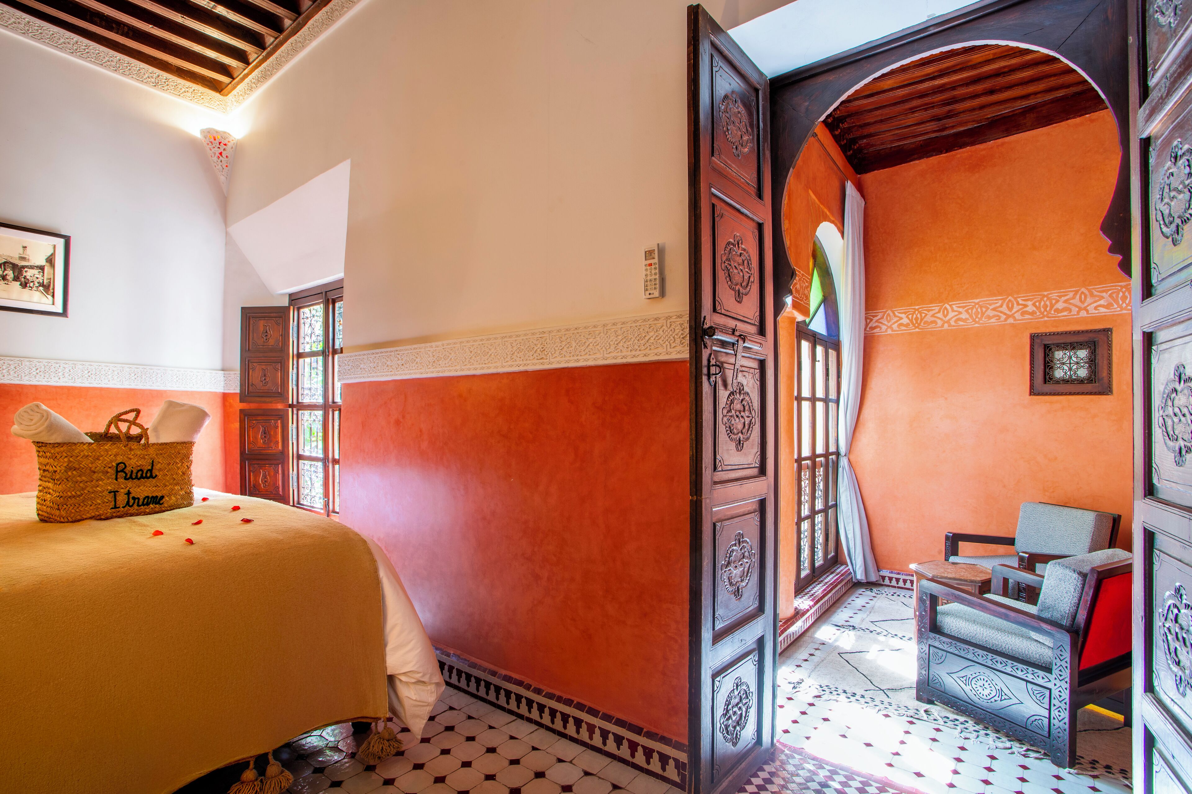 Een hotelkamer met een bed, een rieten mand met handdoeken, een stoel en een decoratieve wand.