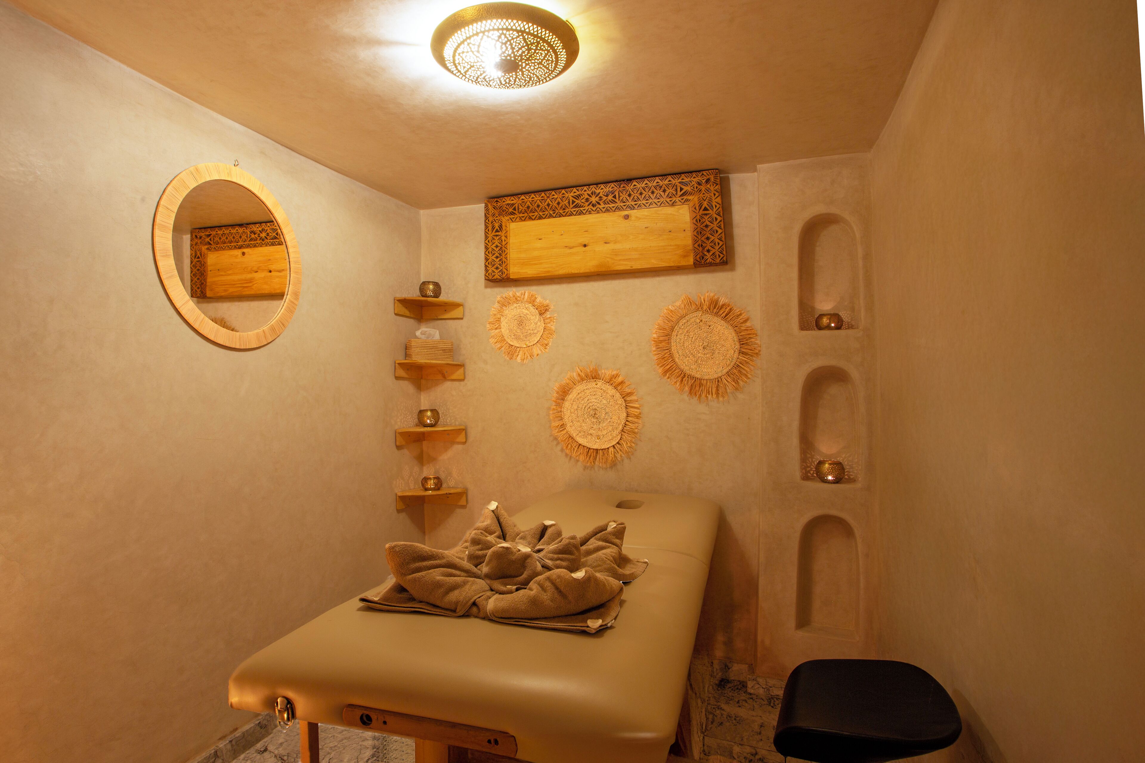 Een spa-ruimte met een massagetafel, een houten plank met decoratieve voorwerpen en wandplanken.