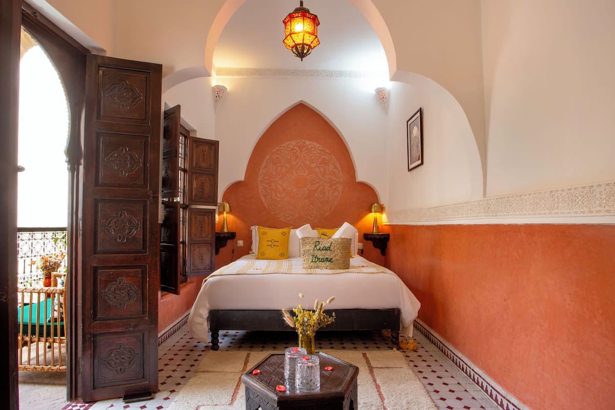 Un dormitorio con una cama grande, una puerta de madera ornamentada y una lámpara de techo decorativa.