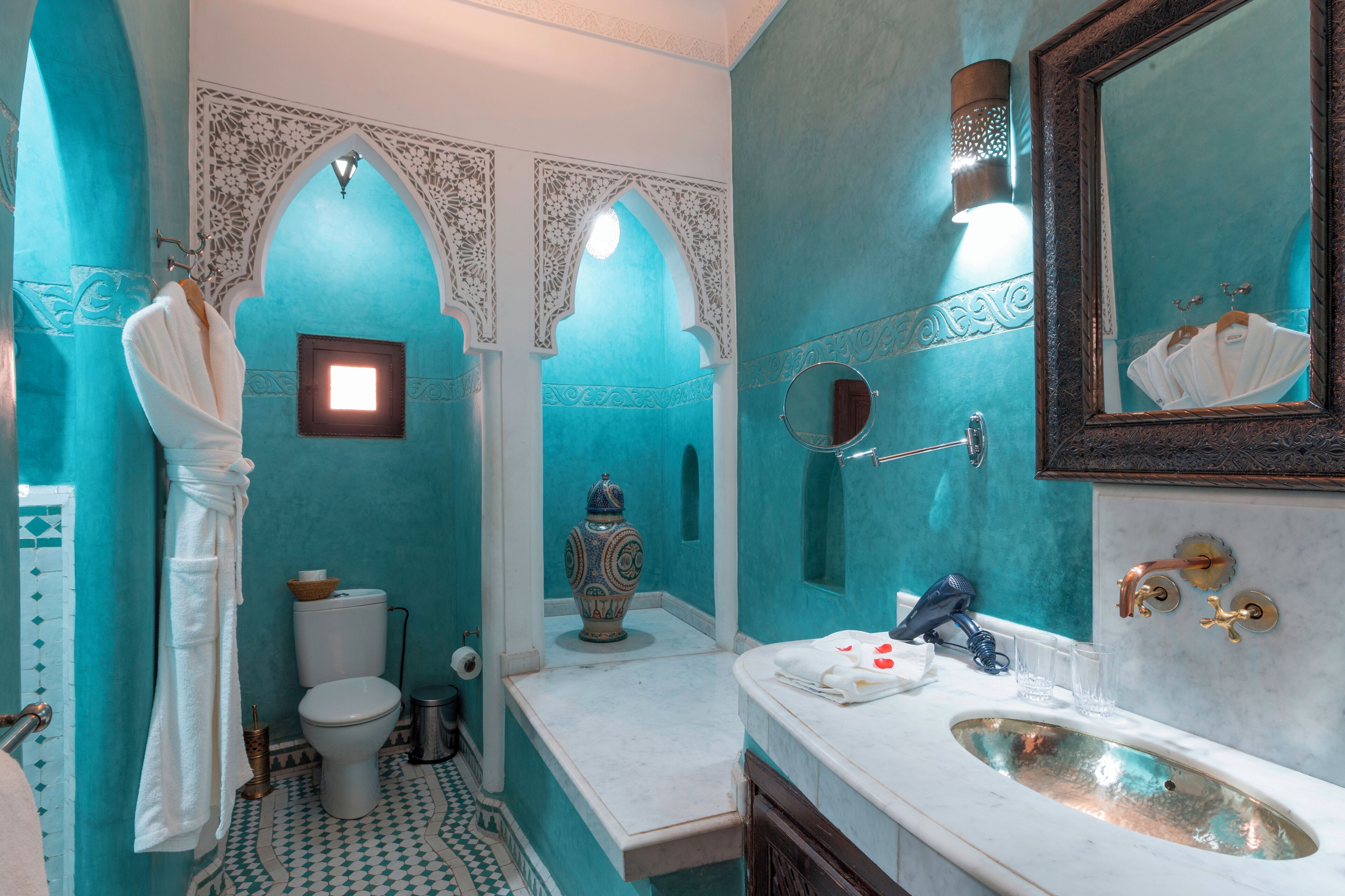 Un baño con paredes turquesa, un lavamanos blanco y un espejo grande.