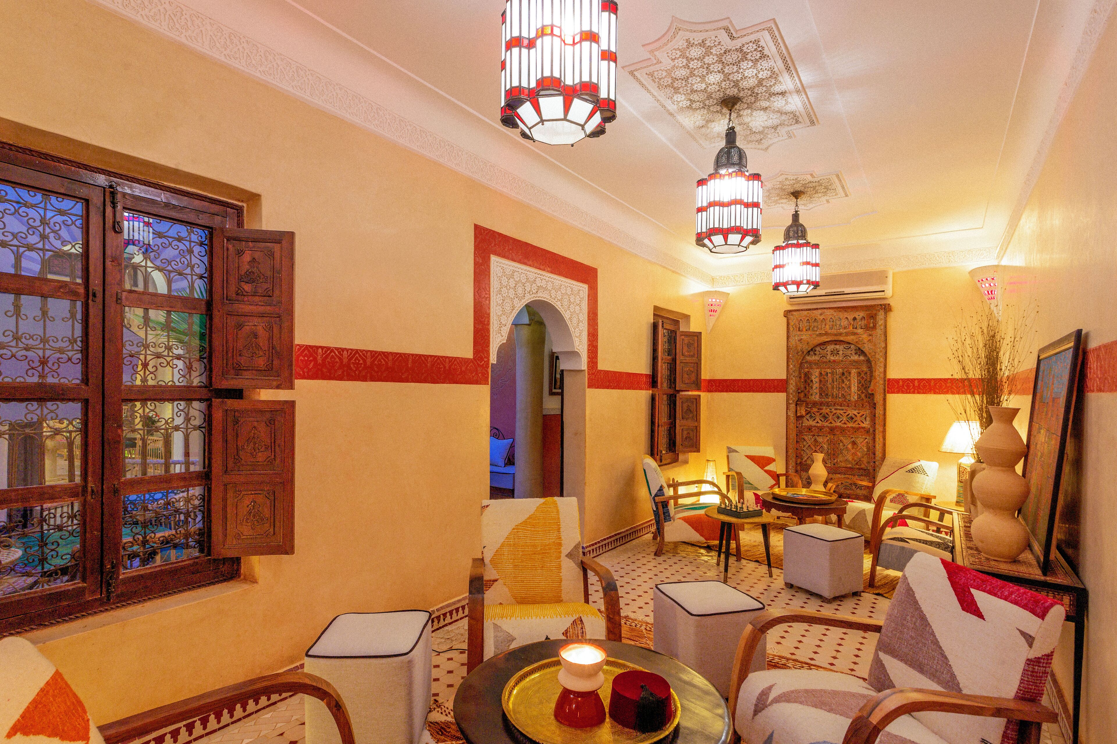 Een klassiek interieur met een gedetailleerd plafond, behang met patronen, en diverse zithoeken, waaronder een bank en stoelen.