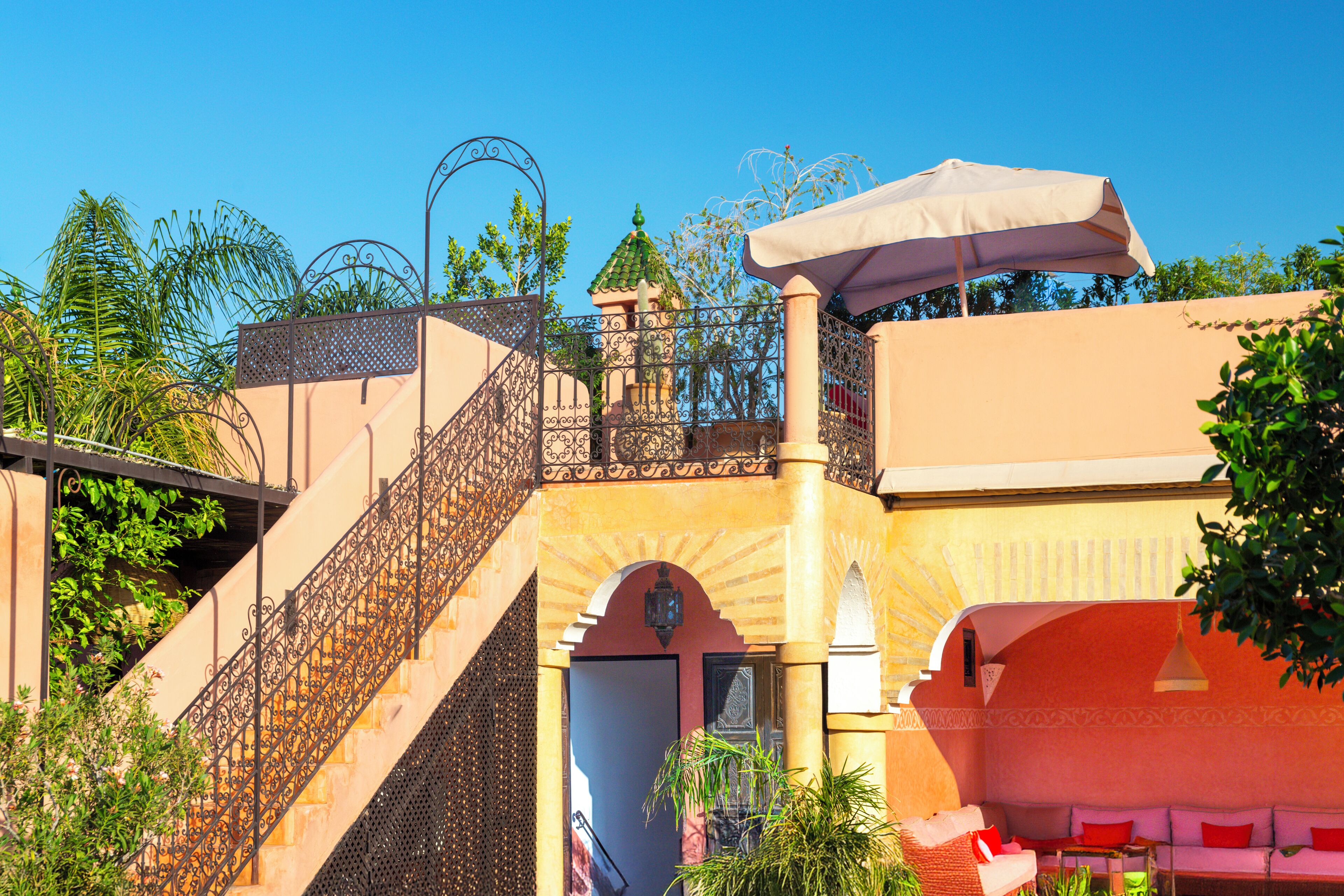 A building with a staircase, a balcony, and a seating area with an umbrella.