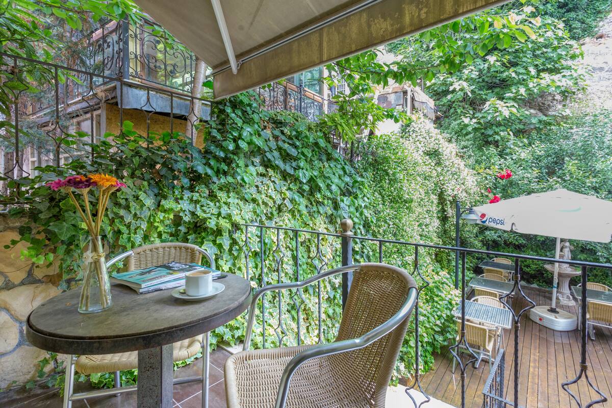 An outdoor patio with wicker furniture, a table with a vase and books, and a Pepsi-branded umbrella.