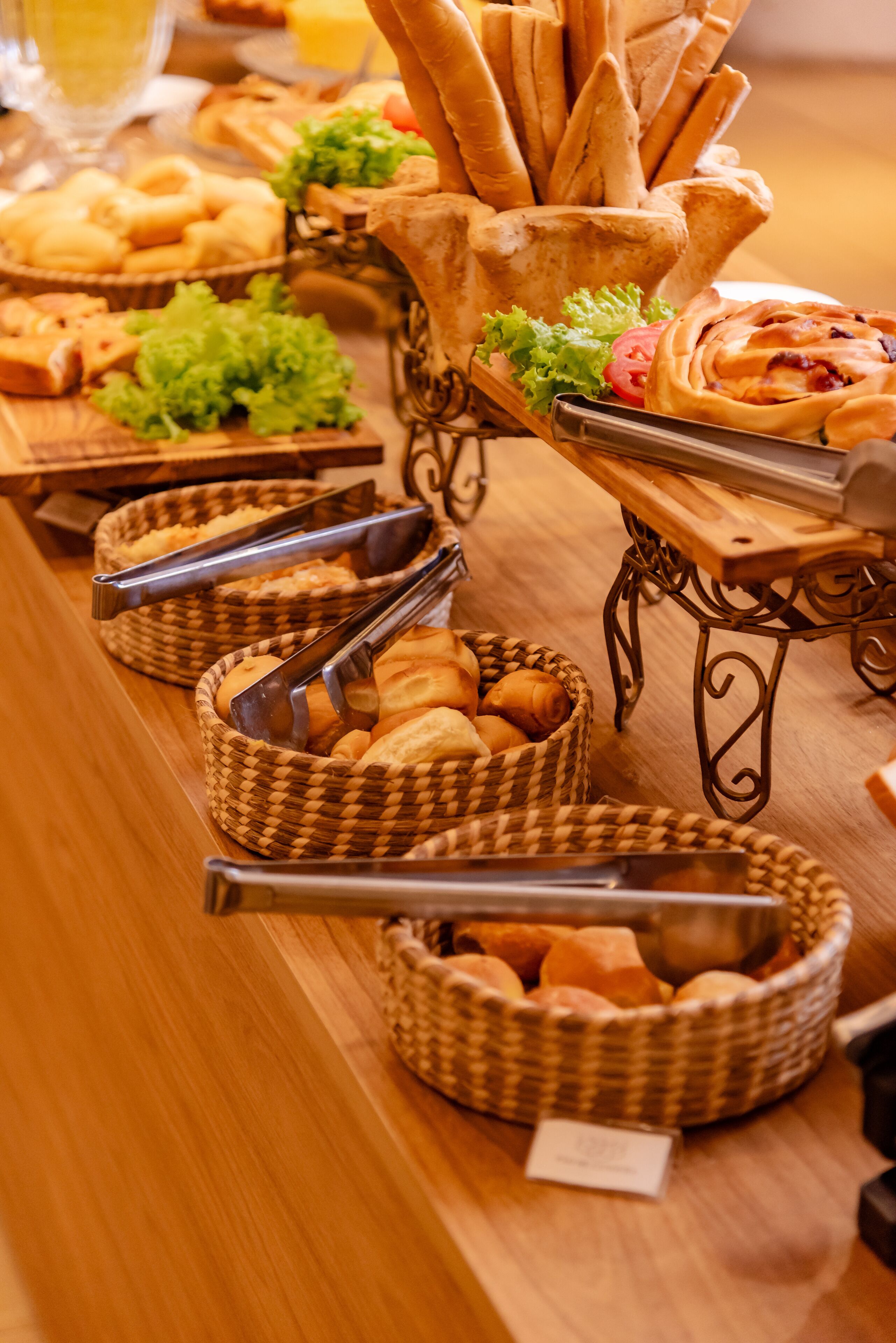 Uma mesa de buffet com diversos pães, pãezinhos e doces.
