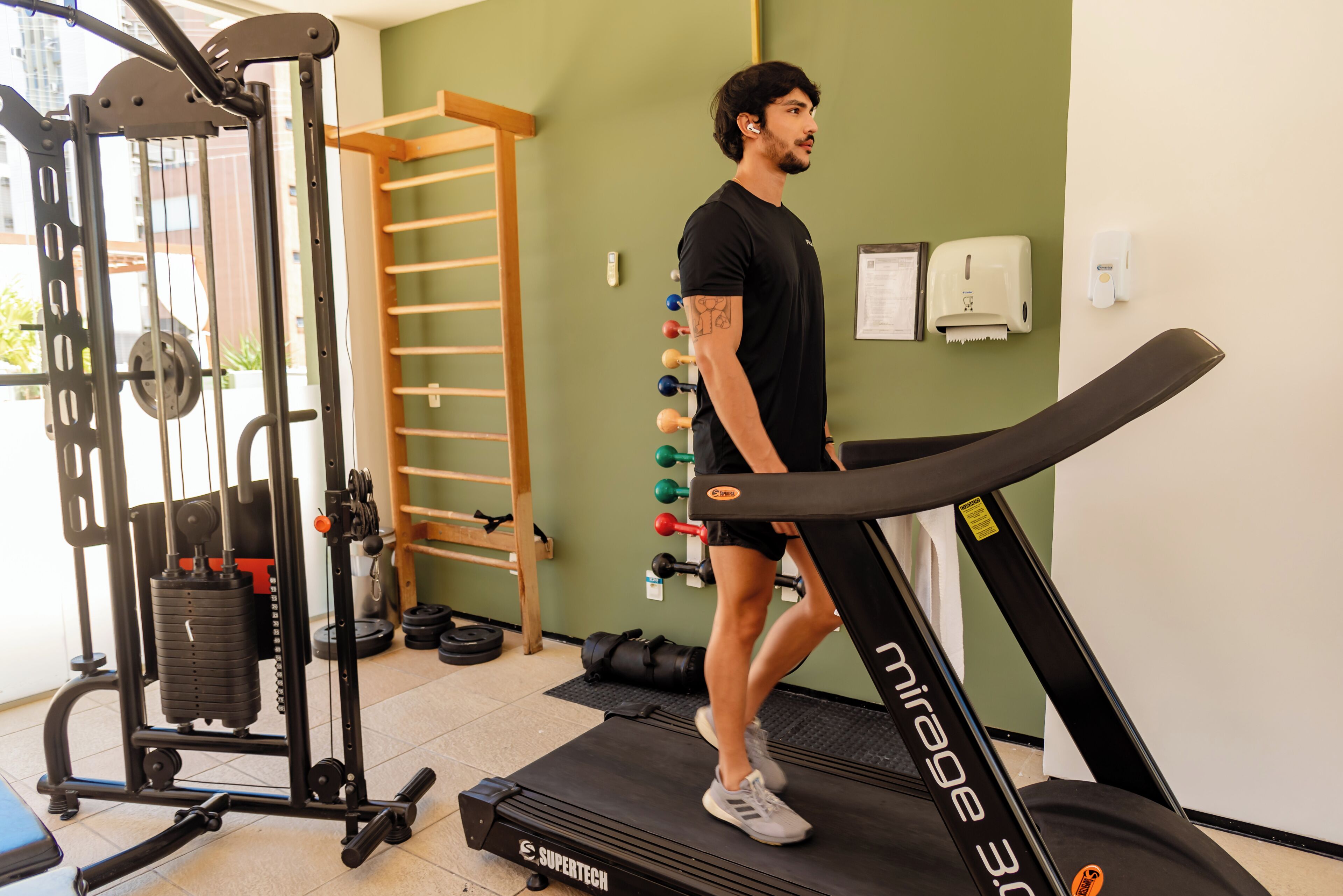 Academia com esteira, equipamentos de musculação e barra para barra fixa.