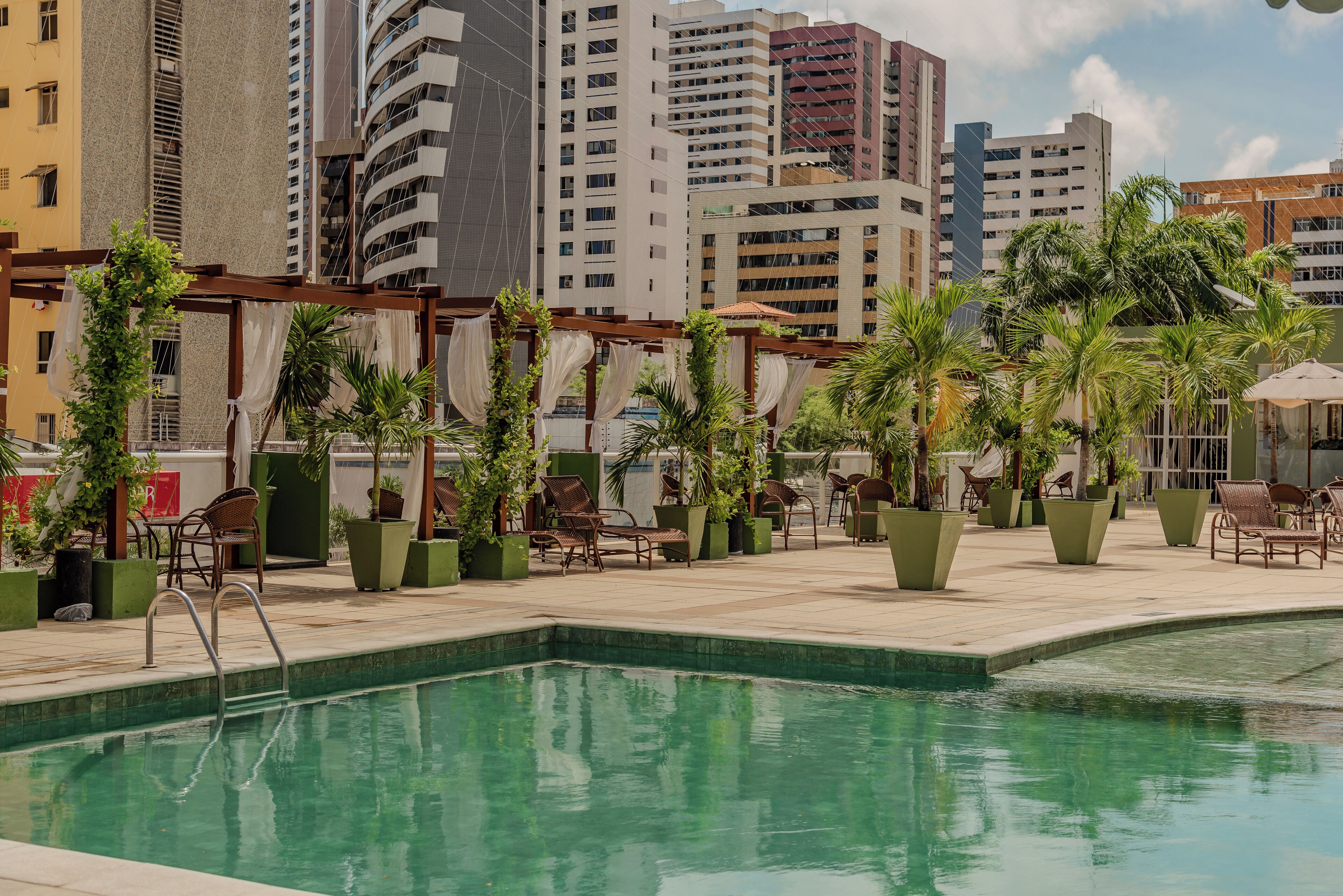 Una piscina al aire libre, sombrillas, sillones reclinables de piscina