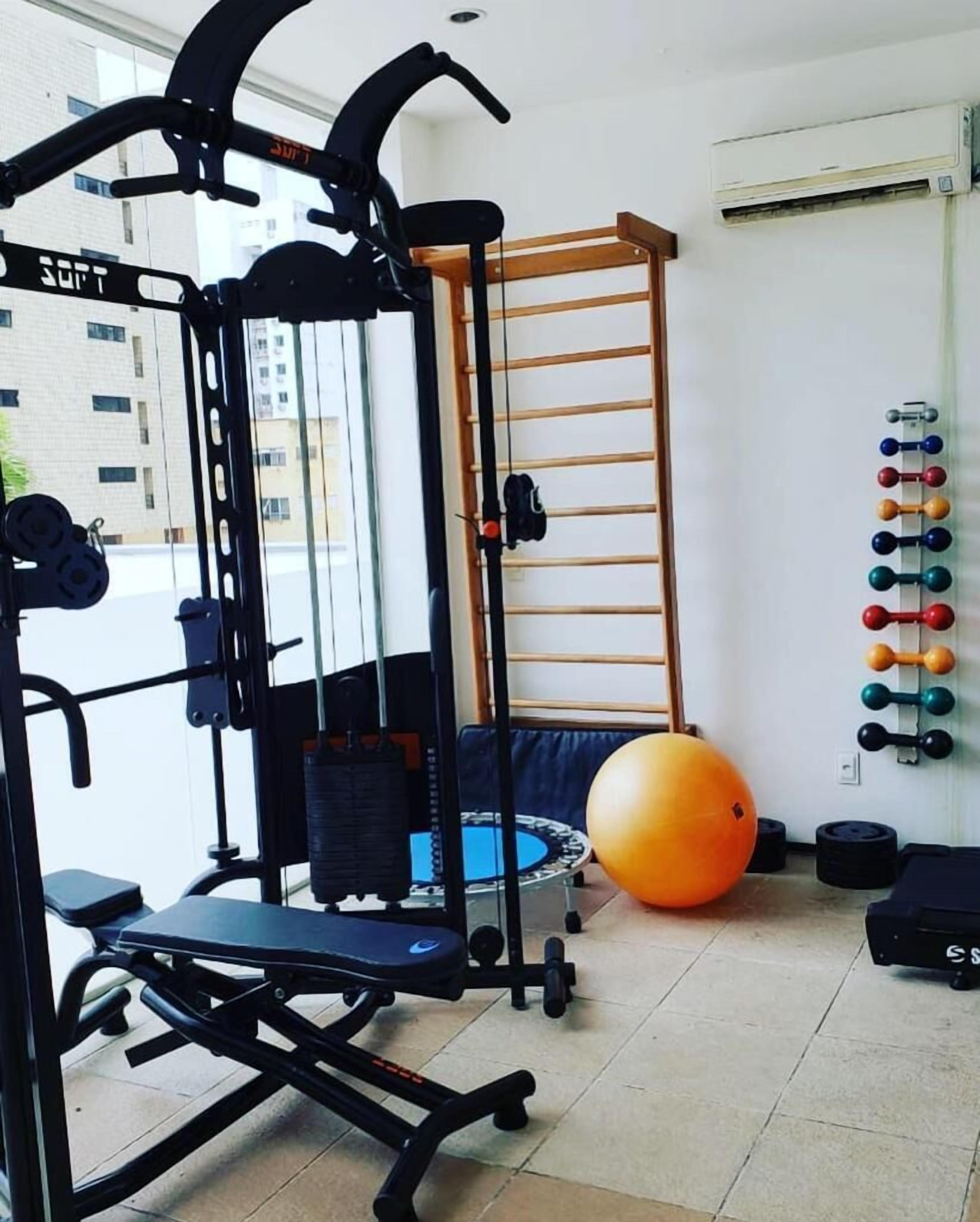 A home gym with a Smith machine, a pull-up bar, a bench, a medicine ball, and a rack of dumbbells.