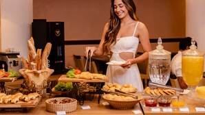 Un bufé con diversas opciones de comida, incluyendo pan, pasteles y un dispensador de agua.