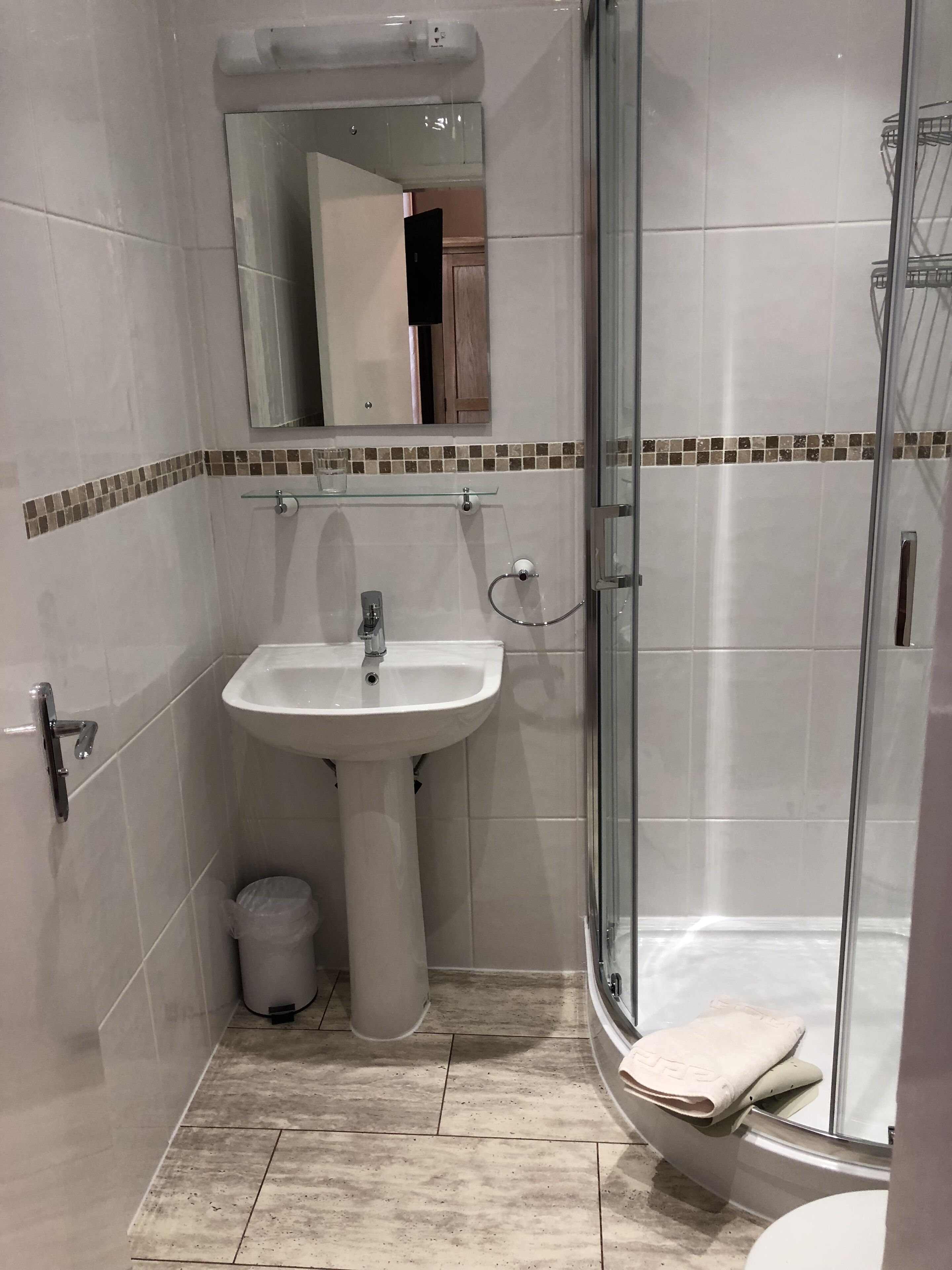A bathroom with a sink, mirror, and shower.