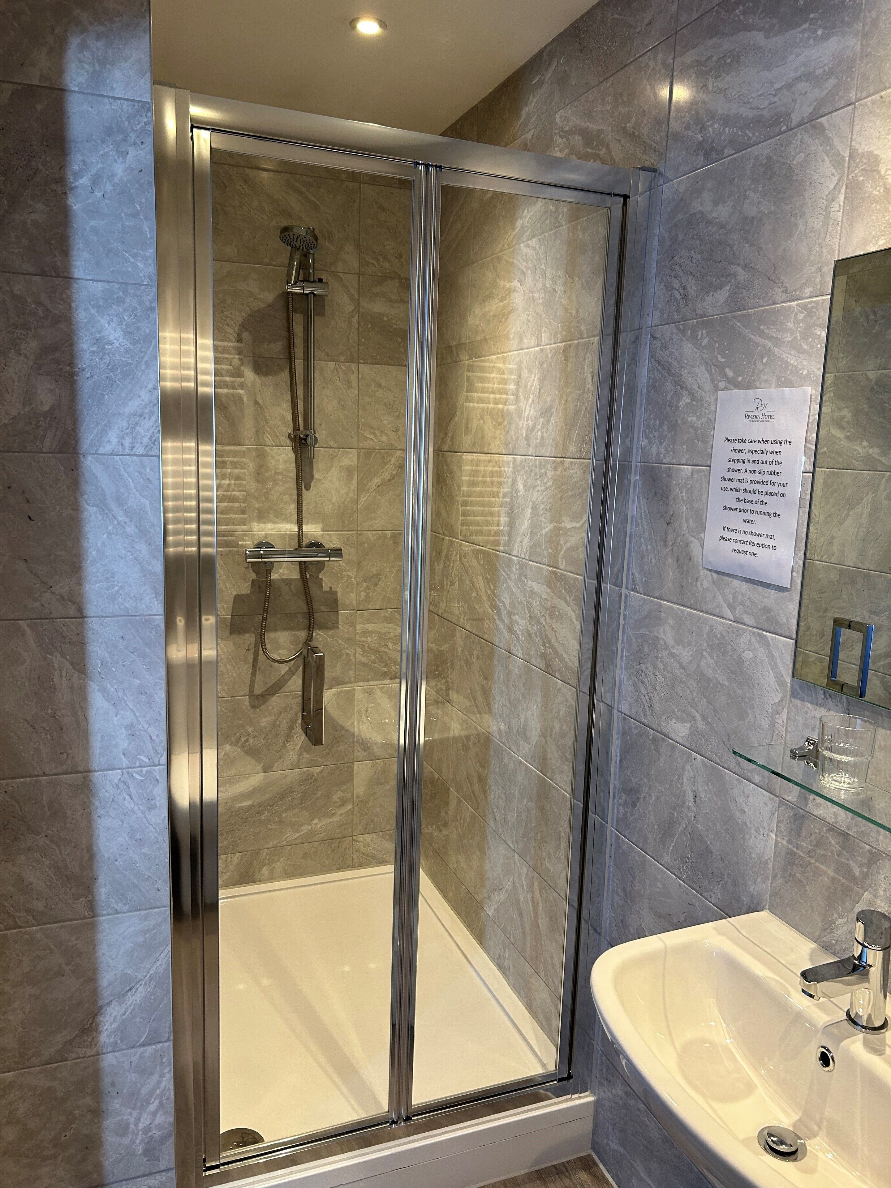 A modern bathroom with a glass-enclosed shower, a sink, and a mirror.