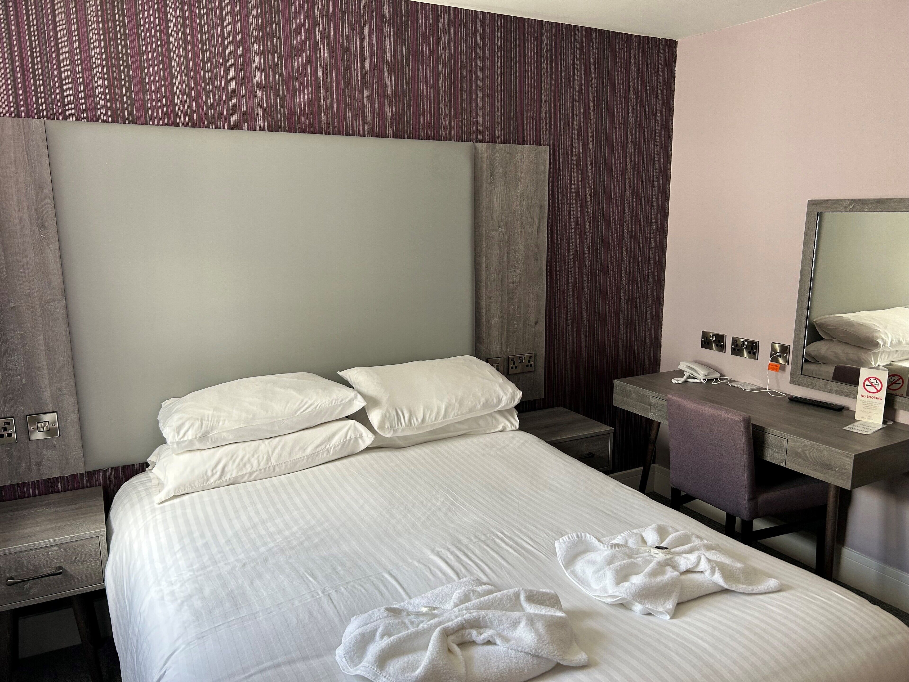 Ein Hotelzimmer mit einem Bett, einem Schreibtisch, einem Spiegel und einem Rauchverbot-Schild.