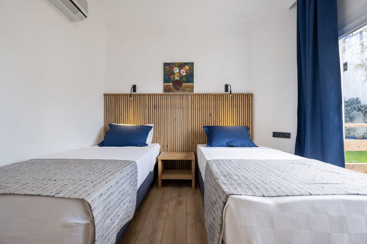 A hotel room with two beds, a wooden headboard, a small table, and a painting on the wall.