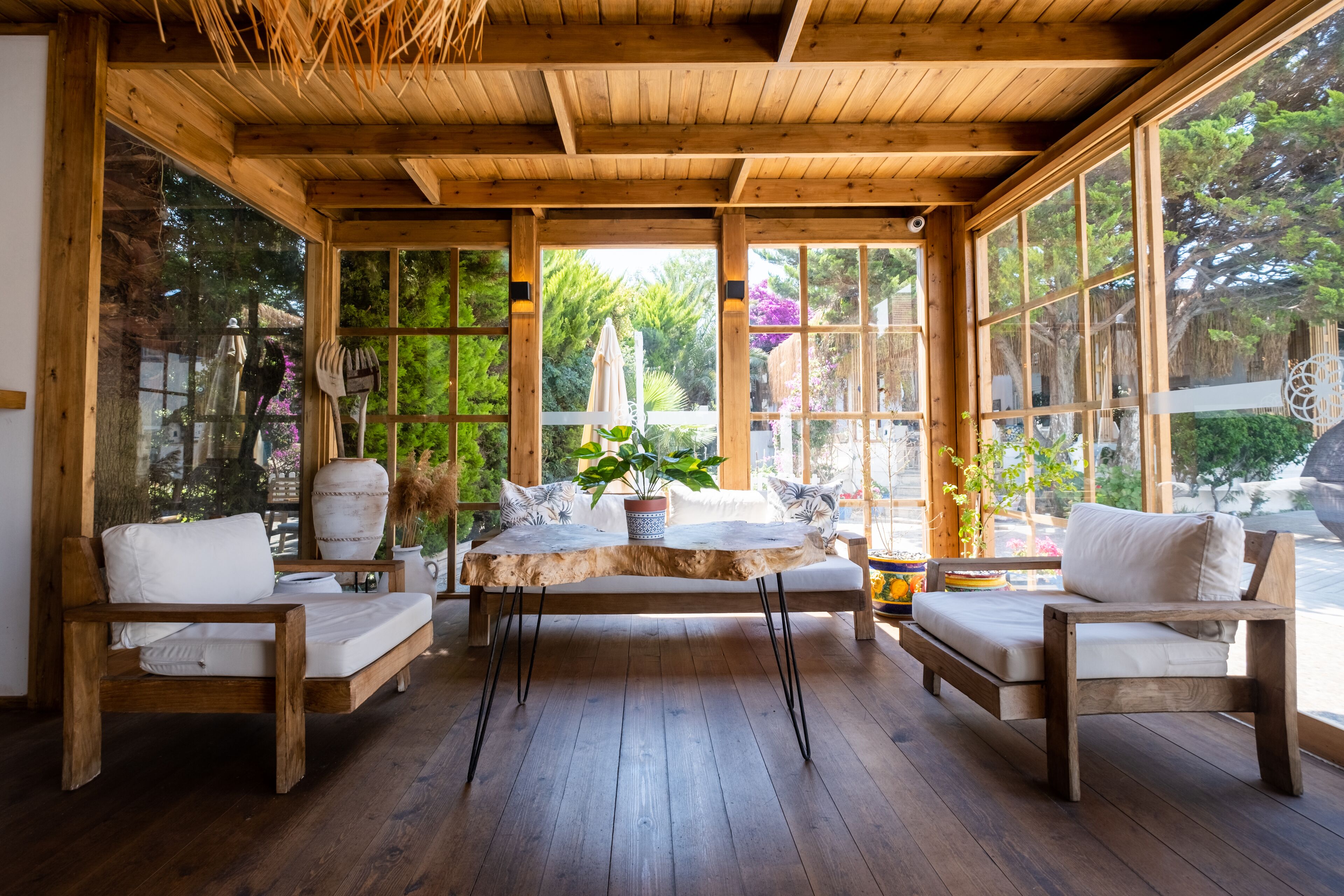 A wooden interior with a central table, two sofas, and large windows.