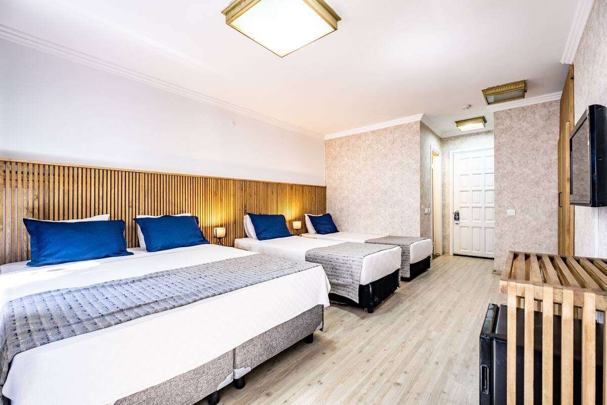 A hotel room with two beds, a wooden headboard, a television, and a door leading to a bathroom.