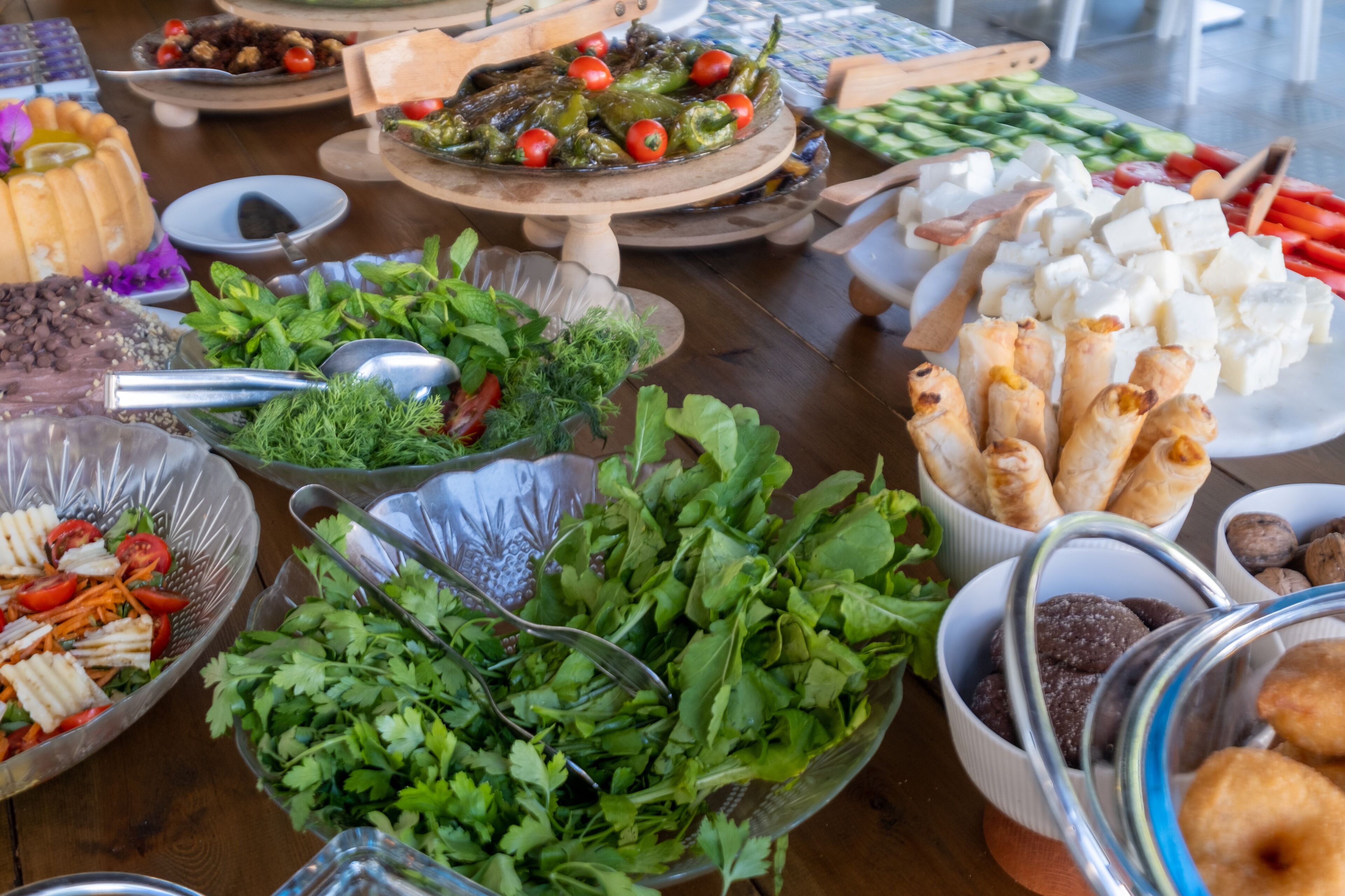 Une table où sont présentés divers aliments, notamment des salades, des légumes et du fromage.