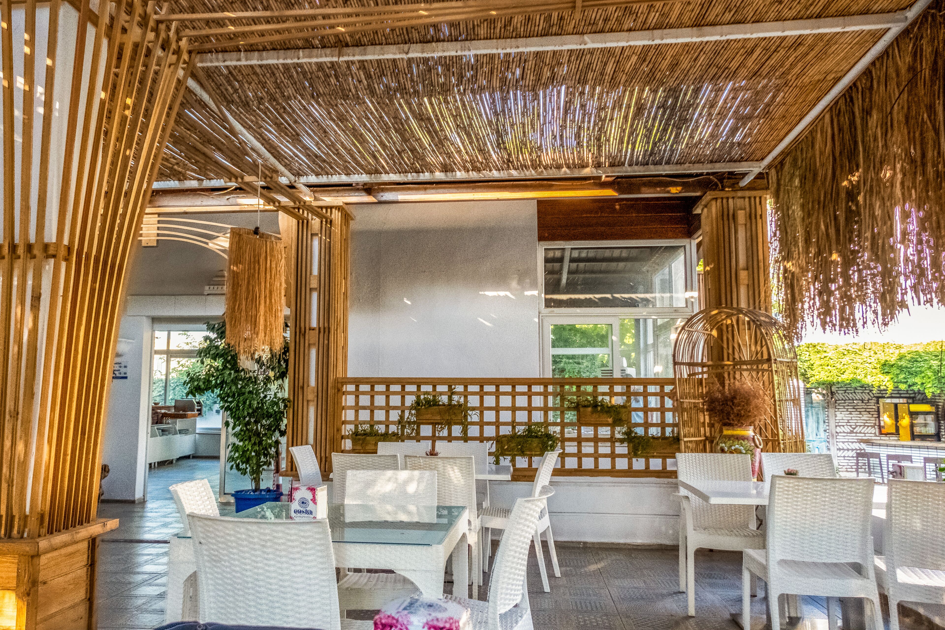 An outdoor seating area with white wicker furniture and a bamboo ceiling.