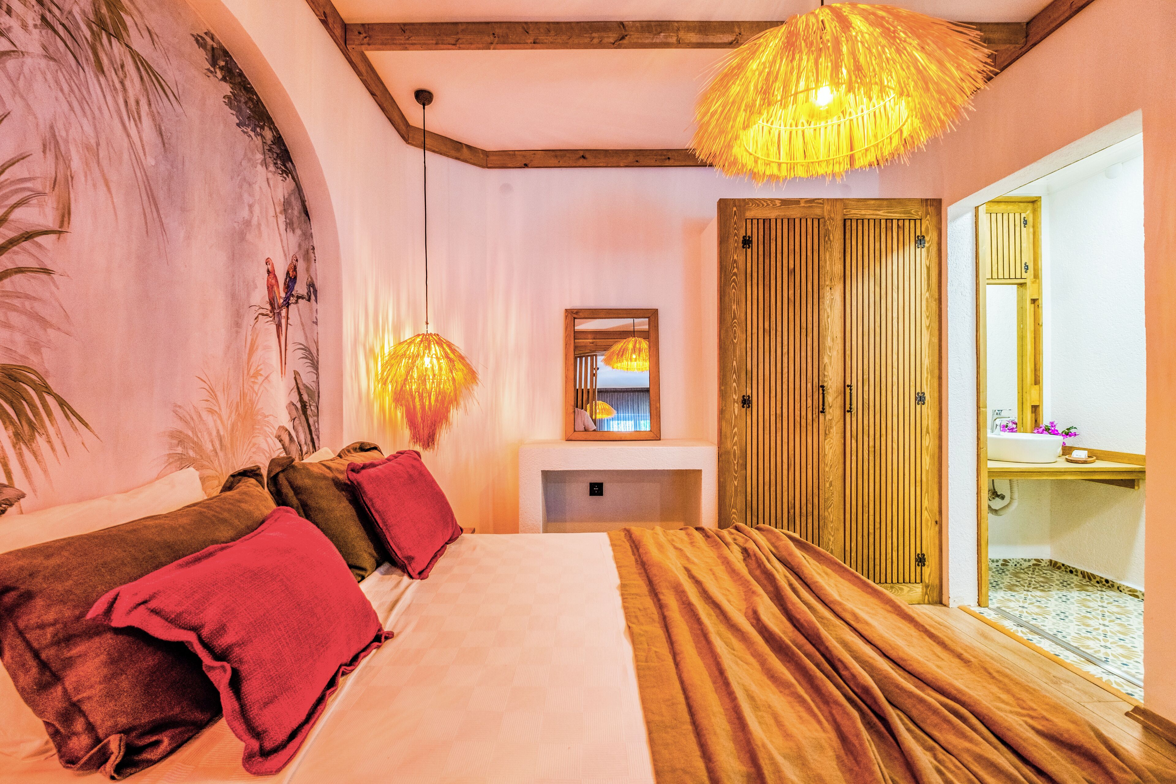 Un dormitorio con cama, armario de madera, espejo y lámpara colgante.