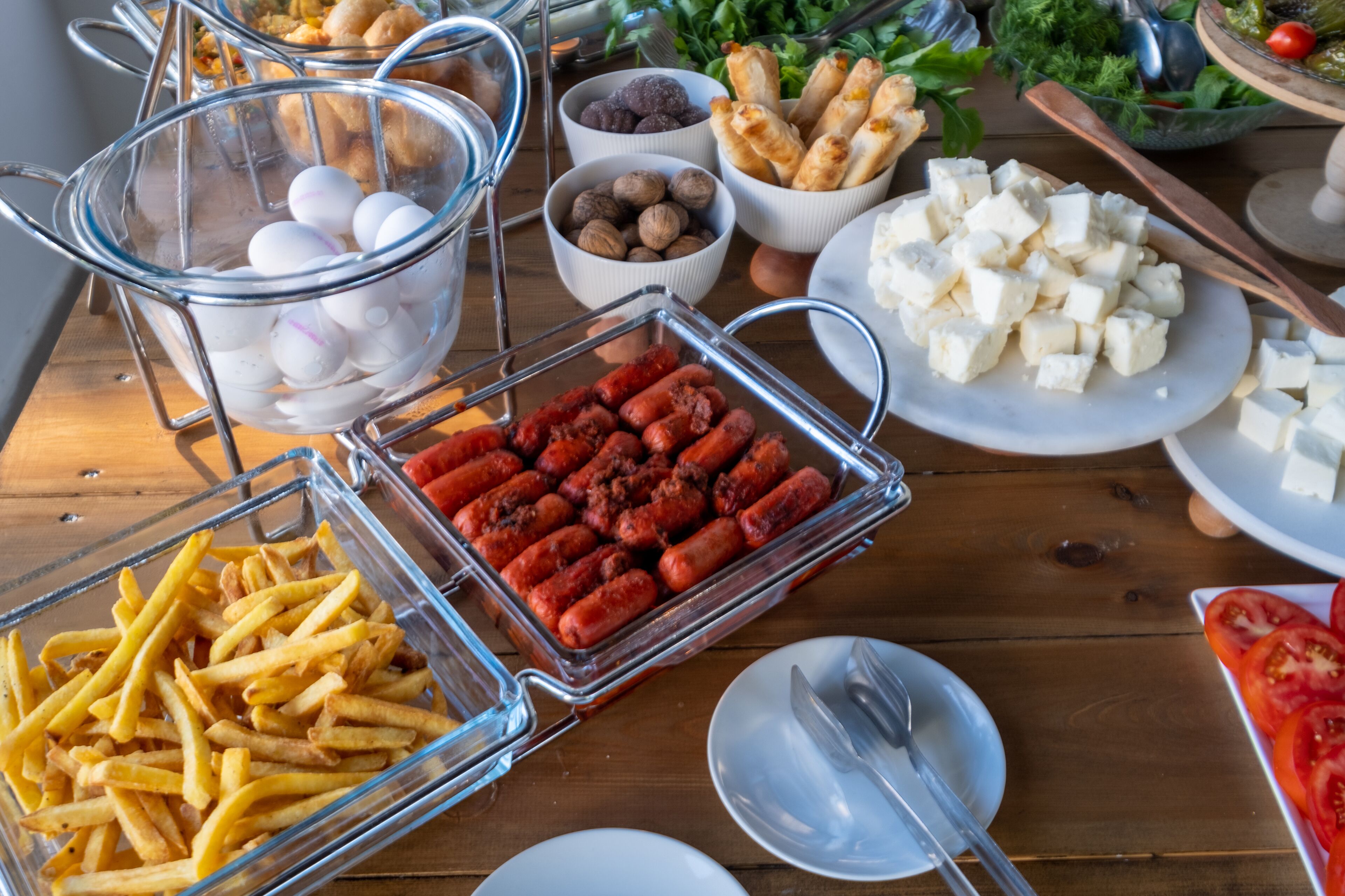 A buffet table with various food items including sausages, cheese, nuts, and bread.