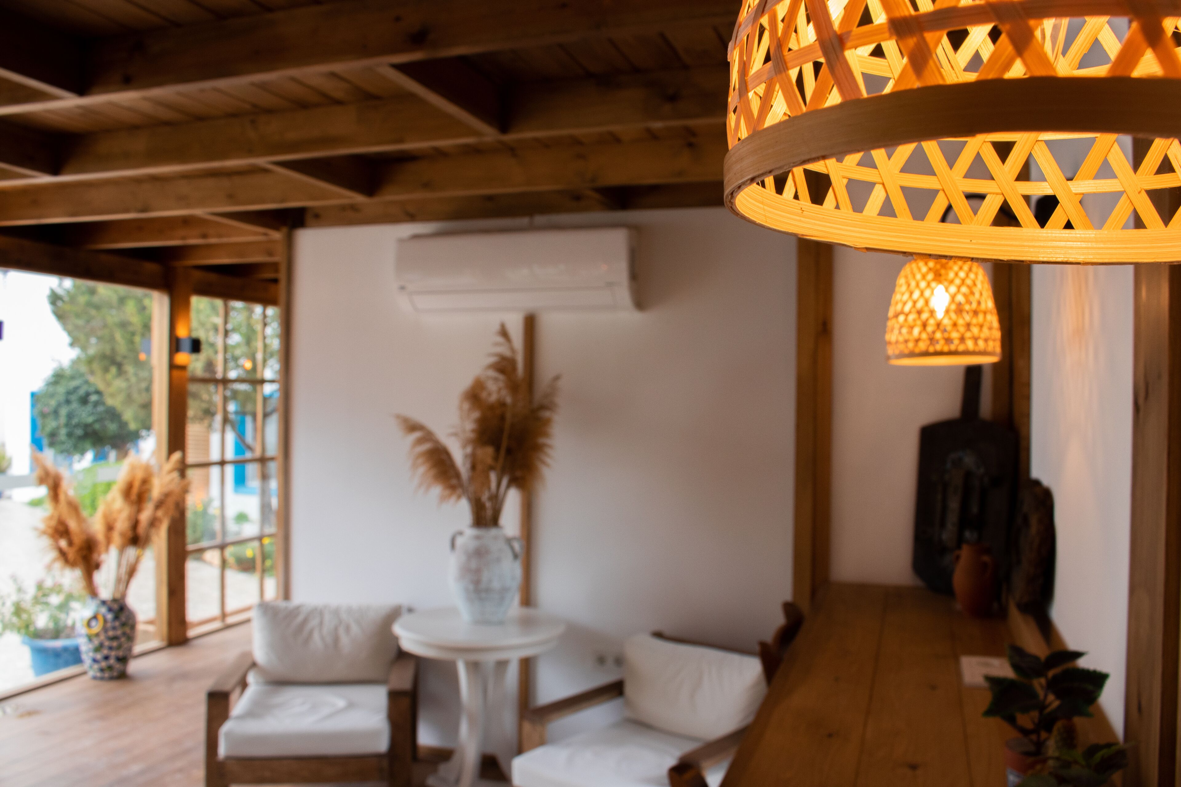 A cozy room with a wooden ceiling, a white sofa, a small round table, and a hanging light fixture.