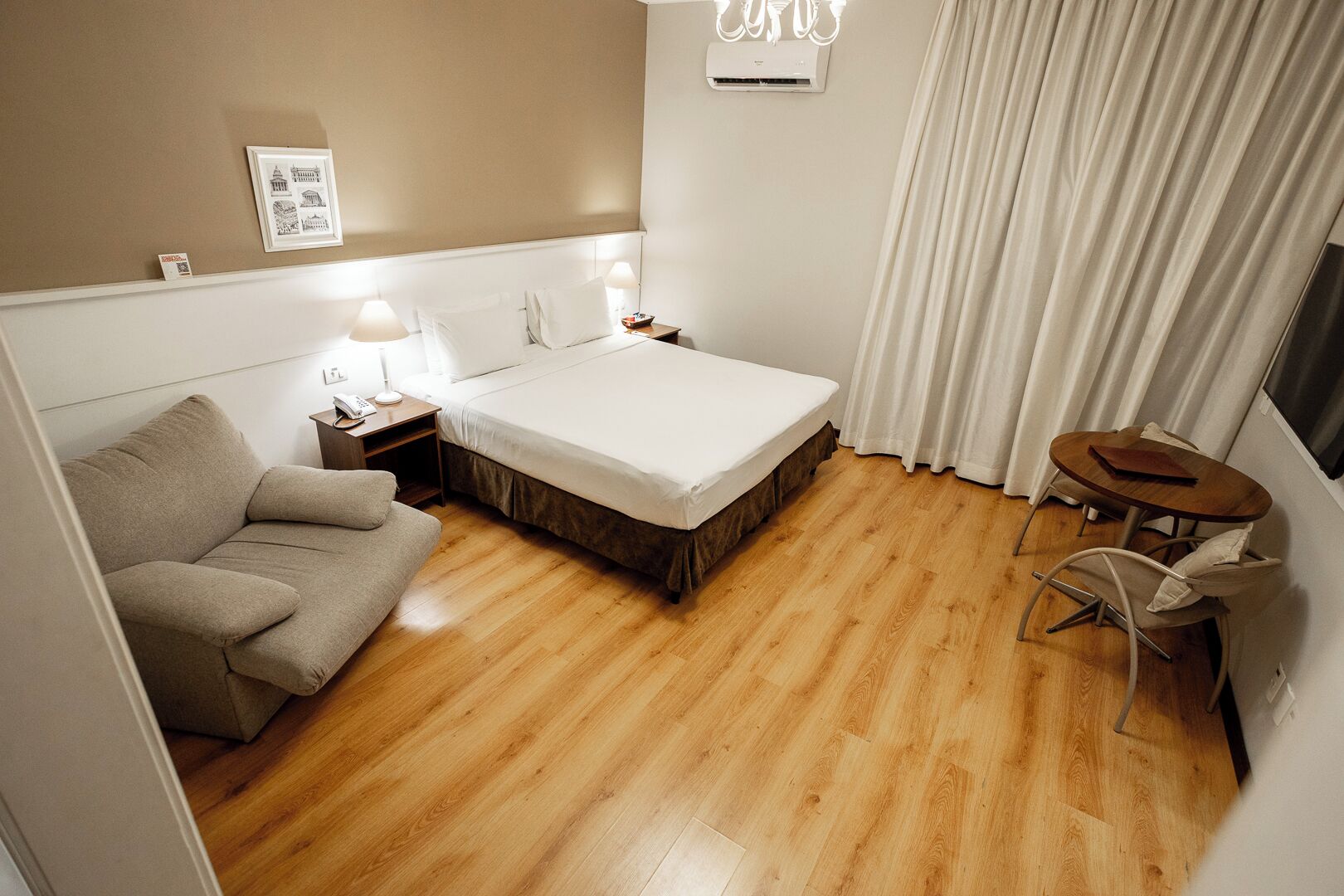 Una habitación de hotel con una cama, un sofá, una mesita y una silla.