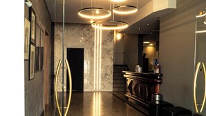 Un vestíbulo moderno con suelo de mármol, un mostrador de recepción y una escalera.