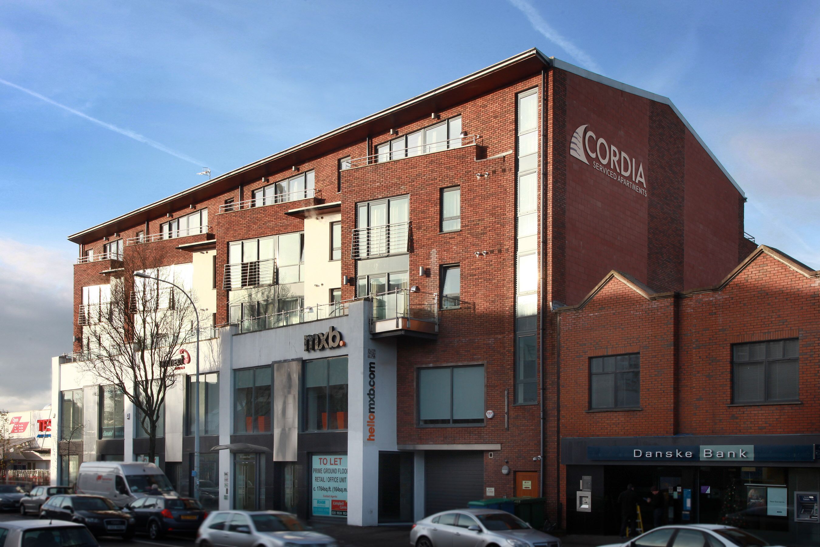 A multi-story building with a prominent Cordia Serviced Apartments sign, a Danske Bank branch, and a visible entrance.