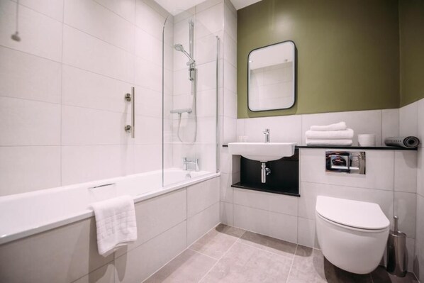 A modern bathroom with a bathtub, shower, sink, and toilet. - Cordia Serviced Apartments (Belfast)