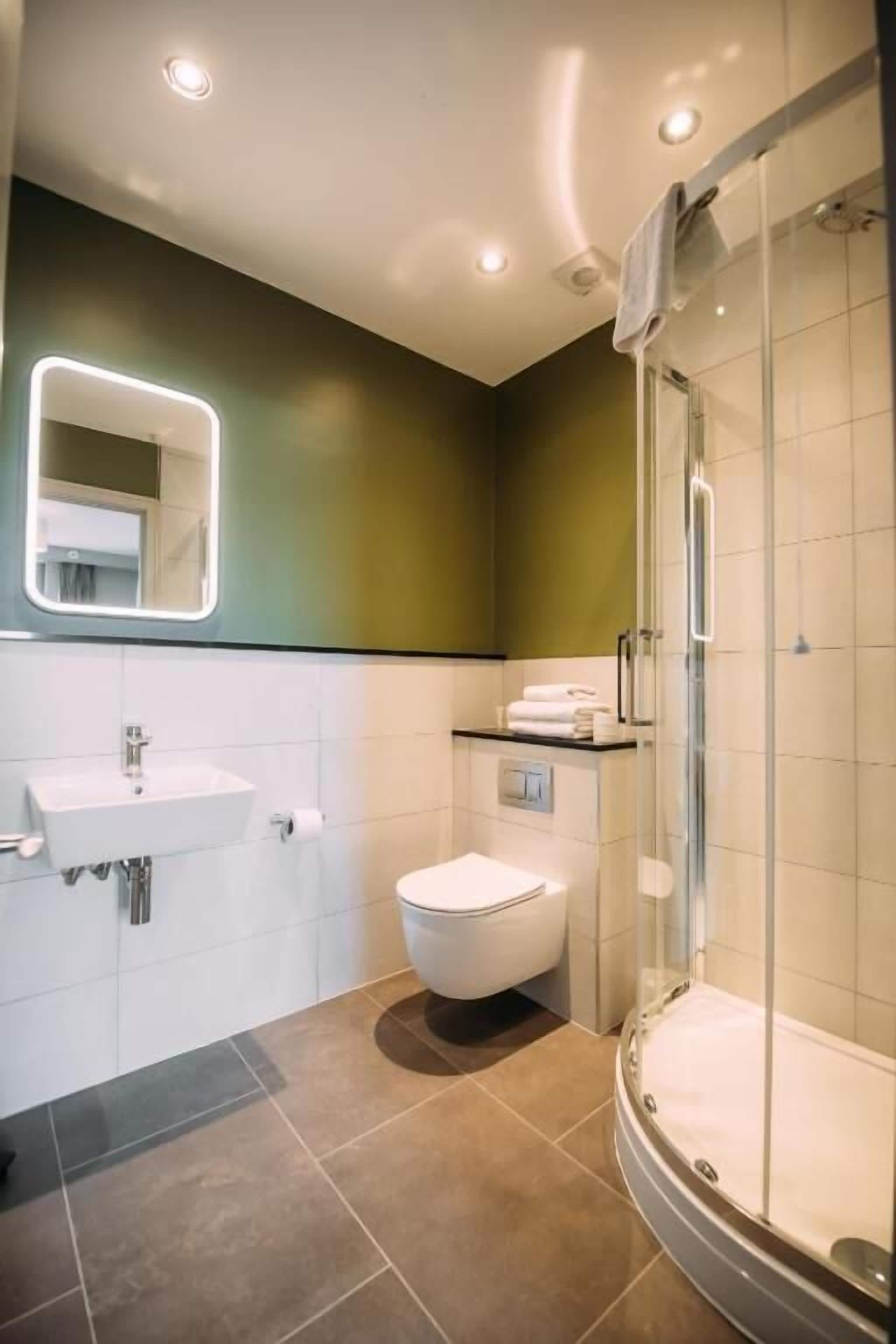 Une salle de bain moderne avec une douche à parois de verre, un lavabo blanc et des toilettes.