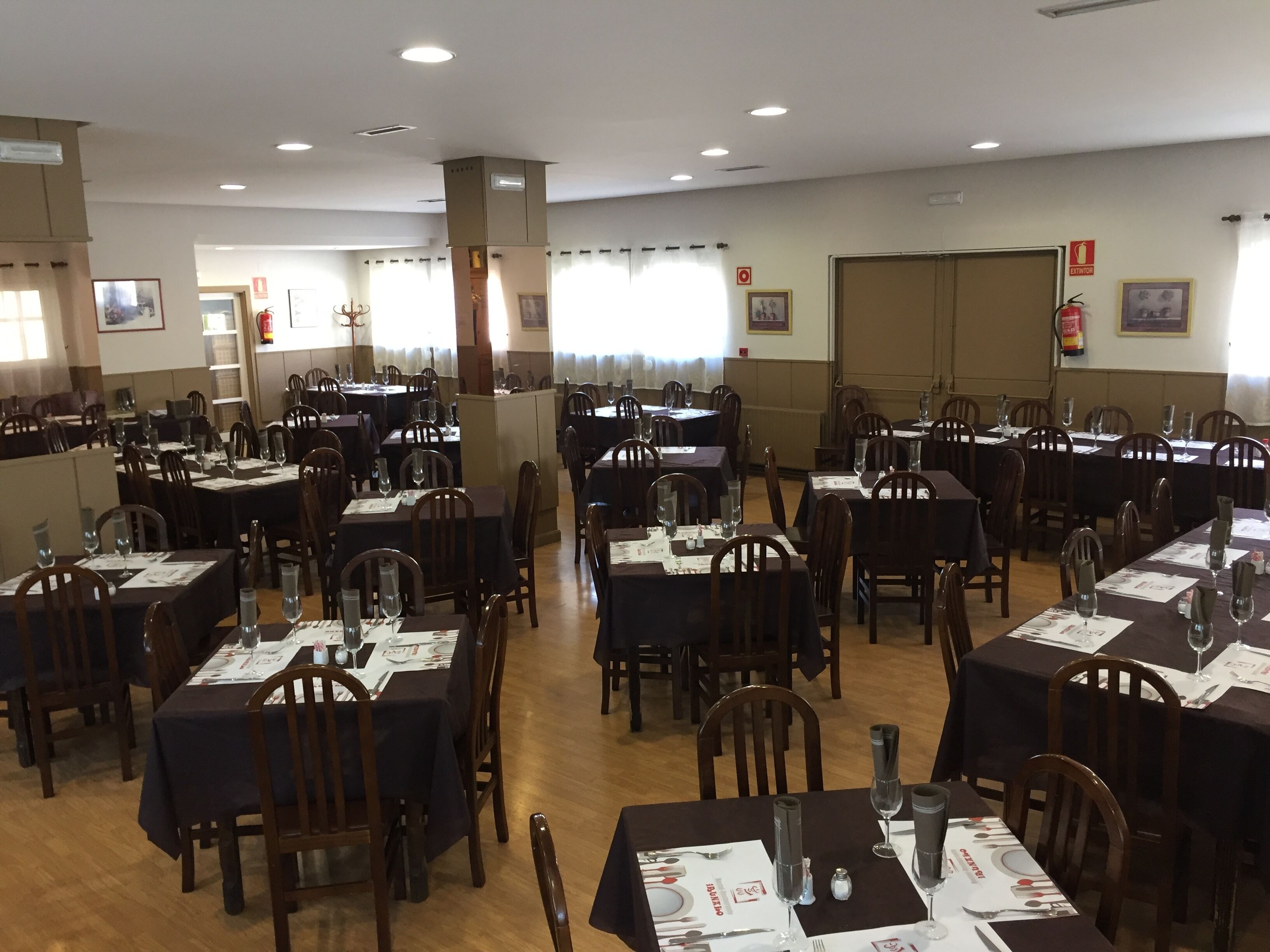 Een restaurant met meerdere gedekte tafels, elk met stoelen en servies.